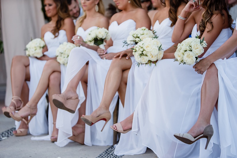 seated bridal party wearing white dresses holding a small bouquet