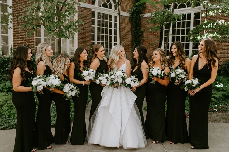 bride wearing white dress and bridal party in black dress holding small white bouquet